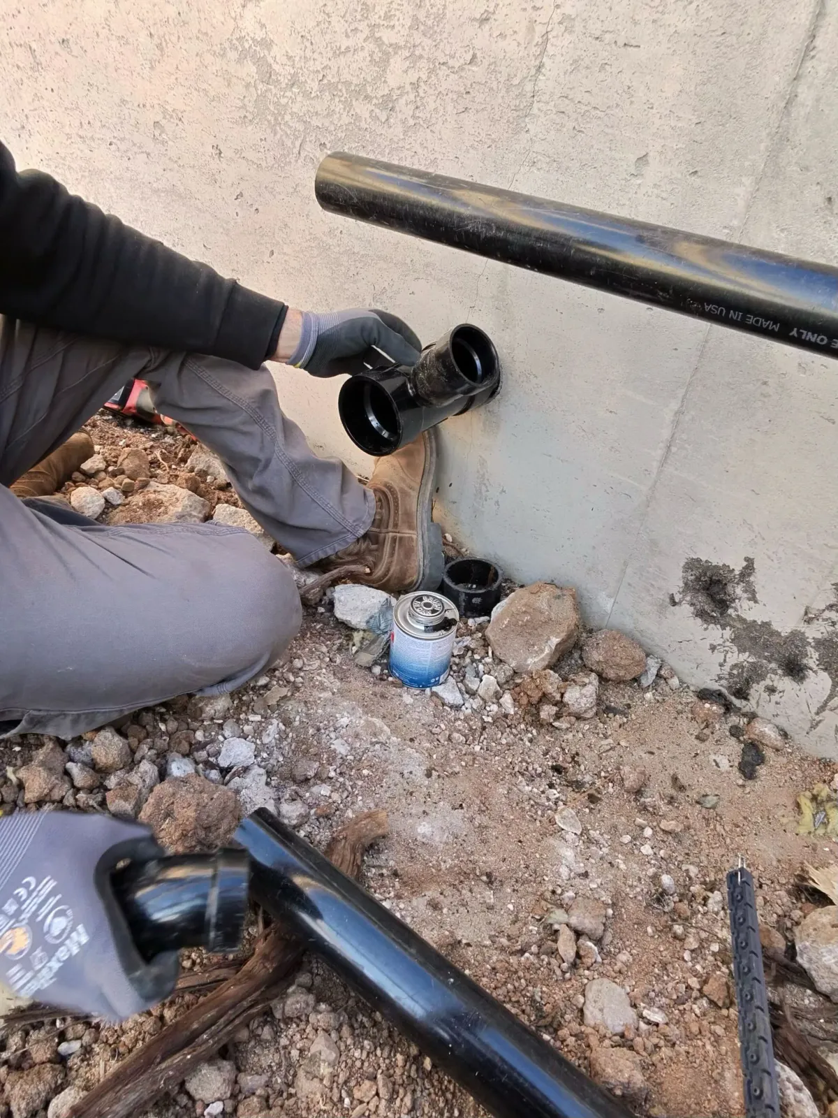 Plumber repairing a leaking pipe dug out at a home foundation in Flagstaff
