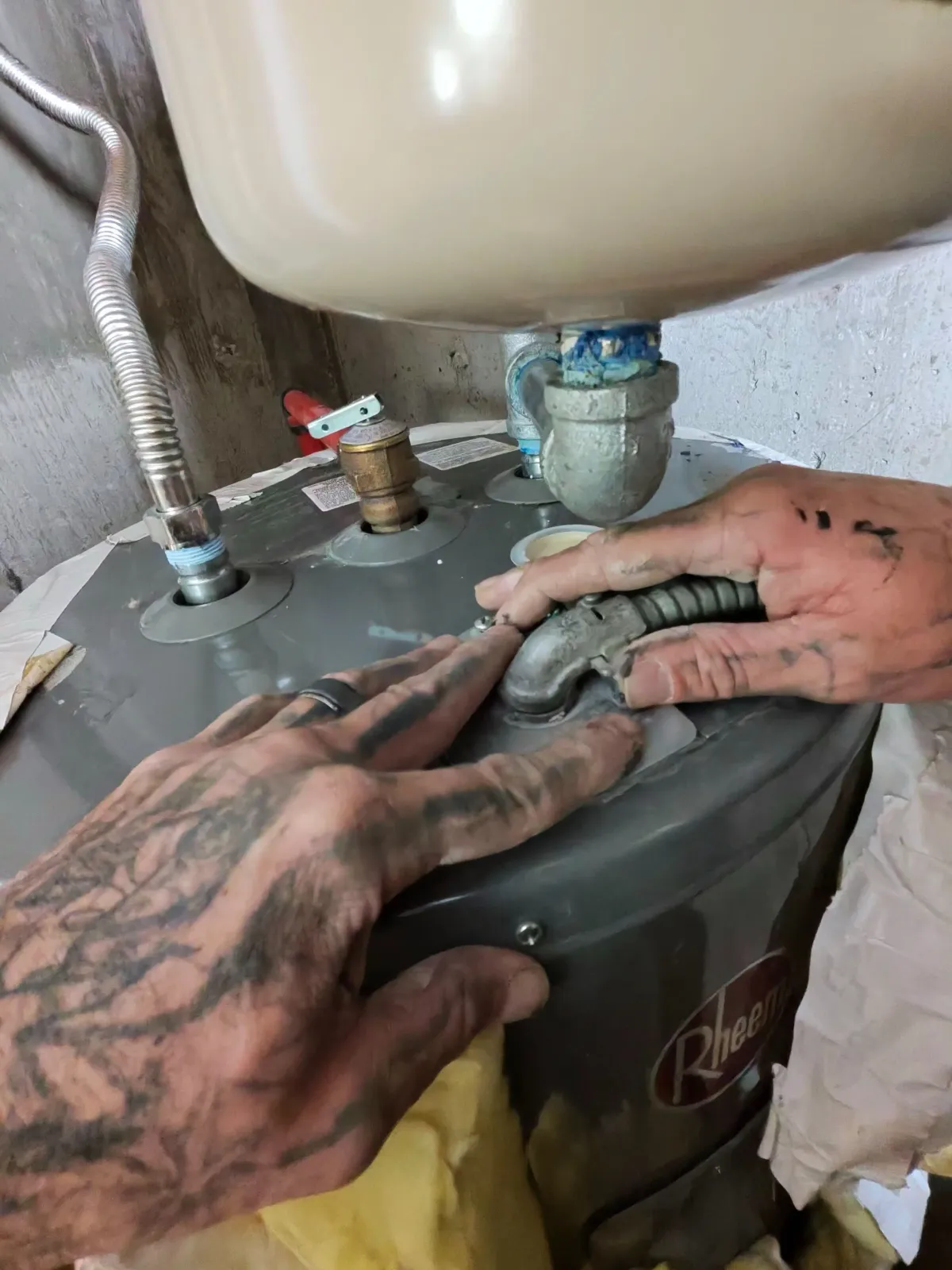 Plumber sealing a leaking pipe fitting on a water heater in Flagstaff